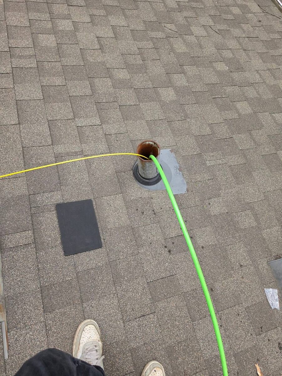 Hydro jetter hose entering a rooftop plumbing vent stack for sewer line drain cleaning in Omaha